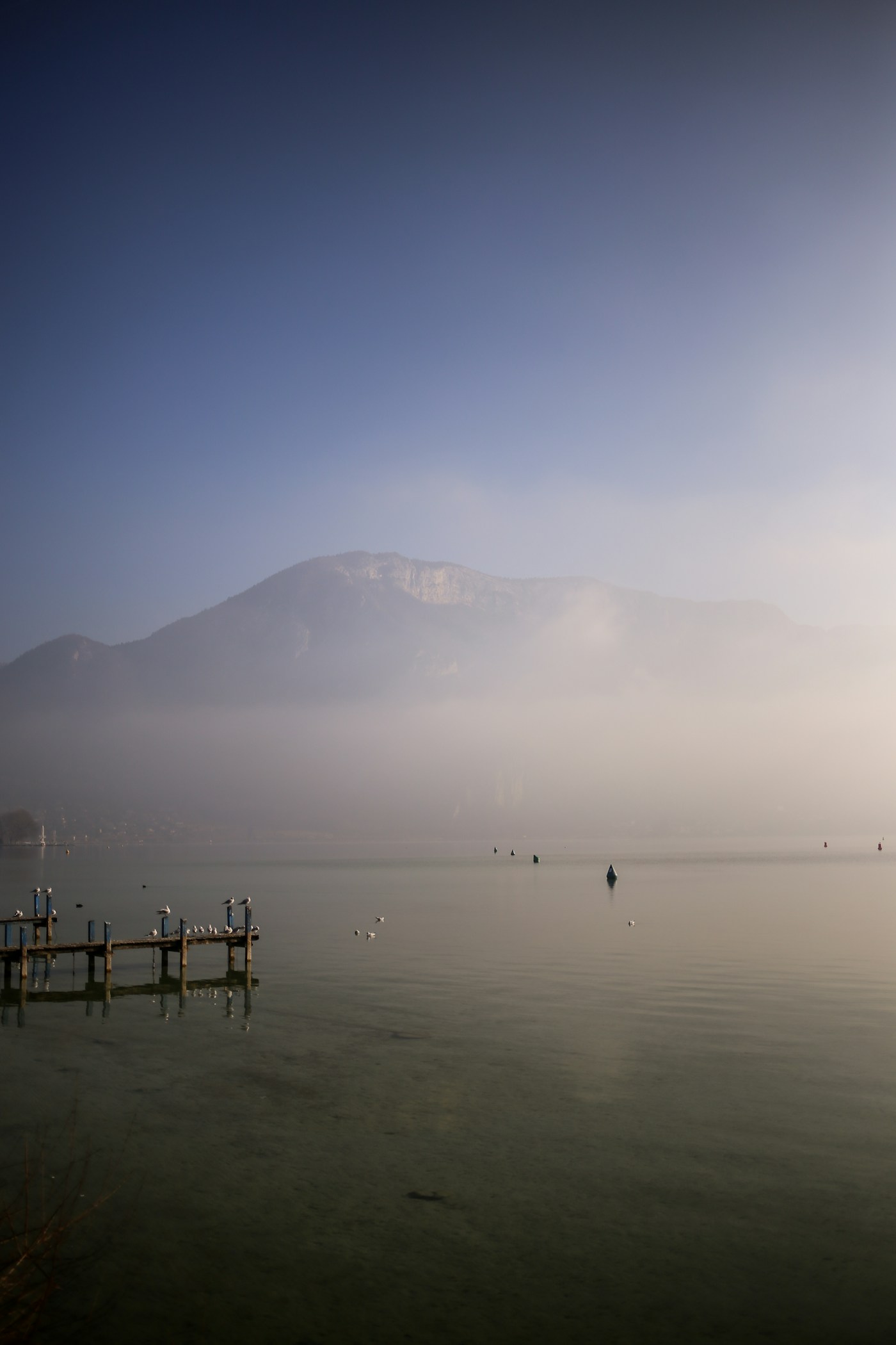 Le lac d’Annecy en hiver, avec un ponton dans la brume. Illustration du paysage autour de l’activité.